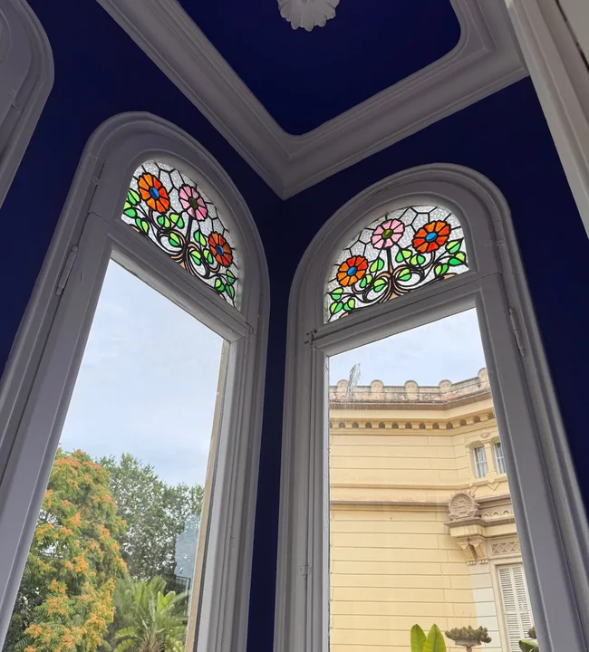 Elegante salón del Hotel Noucentista con vidrieras modernistas y techo azul real