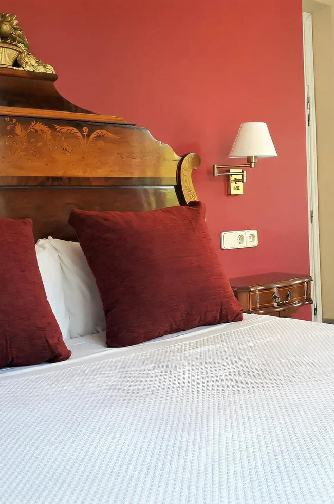 Habitación doble del Hotel Noucentista con cabecero tallado antiguo y suelo de mosaico