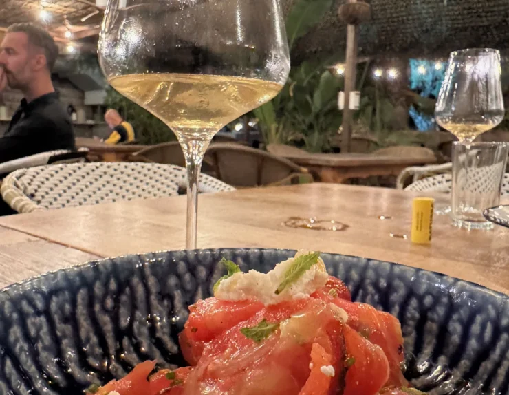 Teller mit frischen Tomaten und ein Glas Weißwein in einer Weinbar in Sitges am Abend