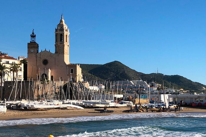 Playa de la Fragata en Sitges un día de verano, con el campanario al fondo