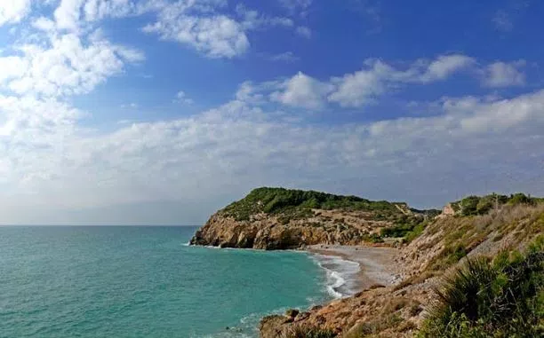 Playa del Home Mort en Sitges, cala nudista al pie de los acantilados