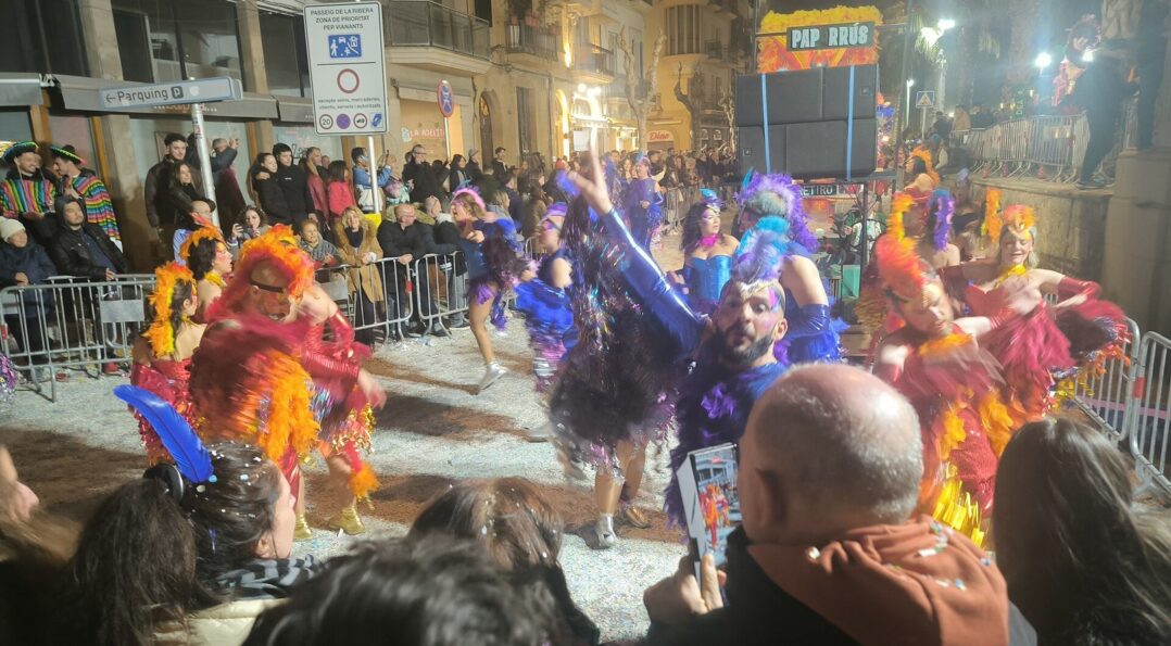 Desfile nocturno del carnaval de Sitges, bailarines con plumas y purpurina en la Rua de l'Extermini