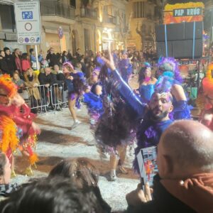 Desfile nocturno del carnaval de Sitges, bailarines con plumas y purpurina en la Rua de l'Extermini