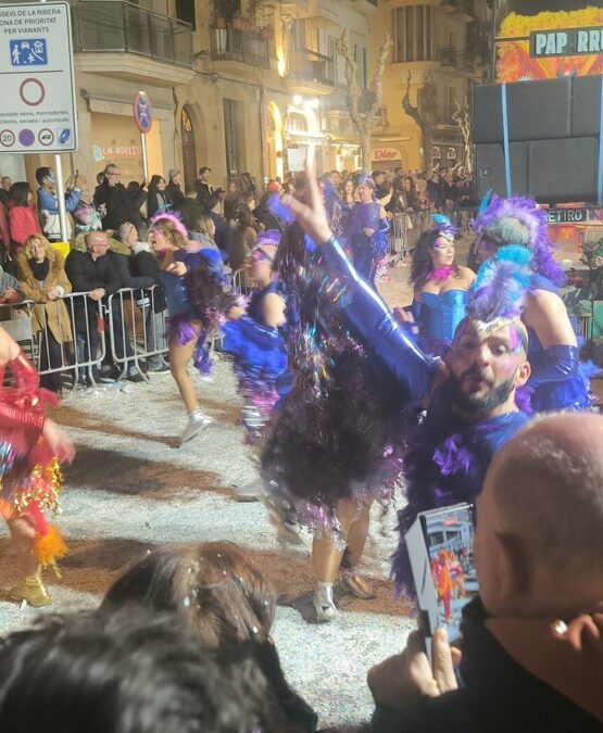 Desfile nocturno del carnaval de Sitges, bailarines con plumas y purpurina en la Rua de l'Extermini
