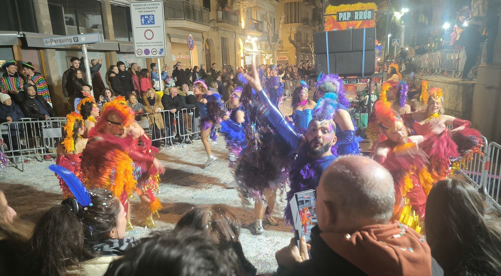 Desfile nocturno del carnaval de Sitges, bailarines con plumas y purpurina en la Rua de l'Extermini