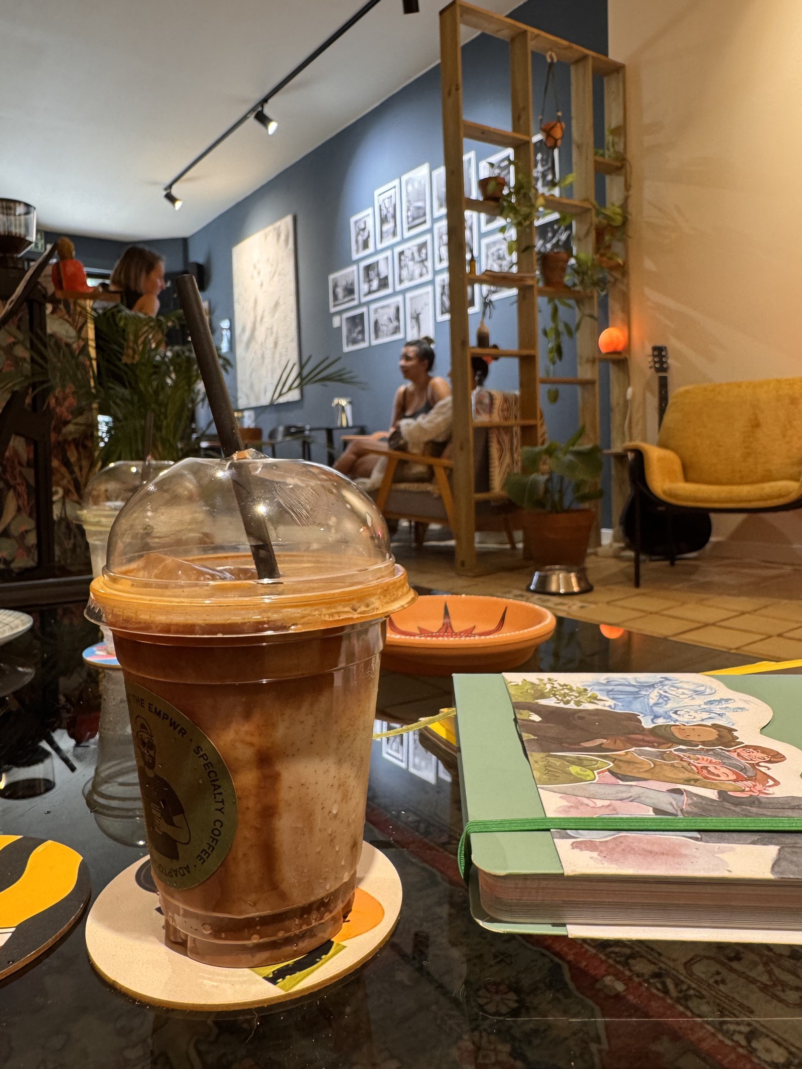Iced Aerocano coffee beside a sketchbook at The EMPWR coworking cafe in Sitges