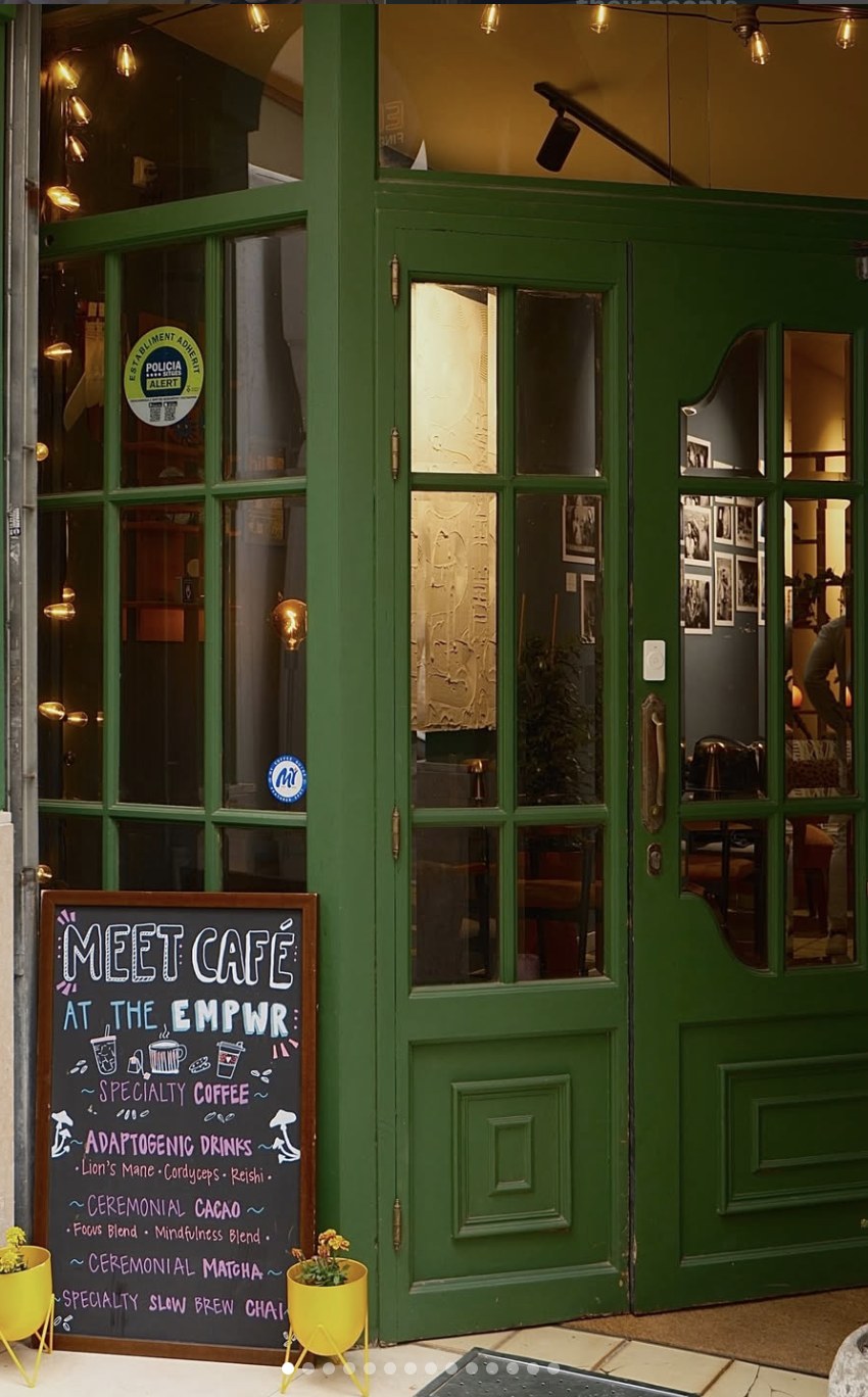 The green entrance and chalkboard menu of The EMPWR specialty coffee and coworking cafe in Sitges