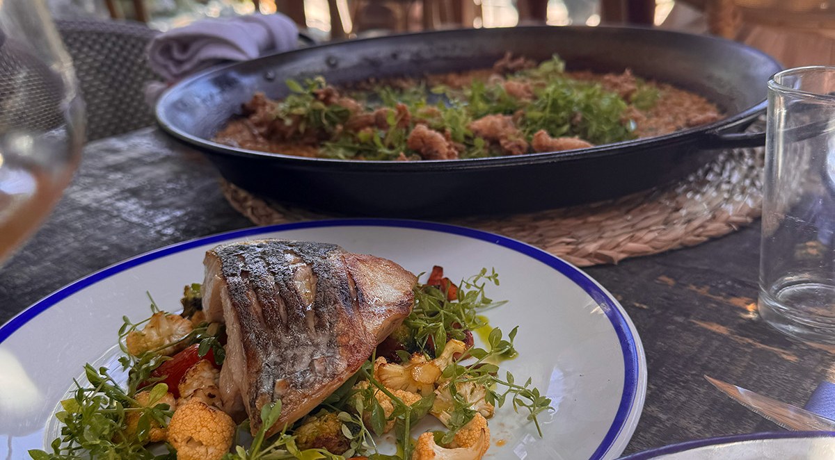 Terrasse eines Restaurants in Sitges mit gegrilltem Fisch und arròs a la sitgetana zum Teilen