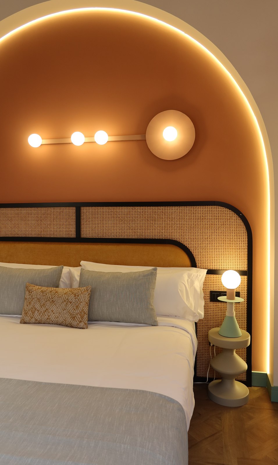 Lit sous une arche lumineuse terracotta, coussins et lampe de chevet design, chambre Superior Casa Beatas