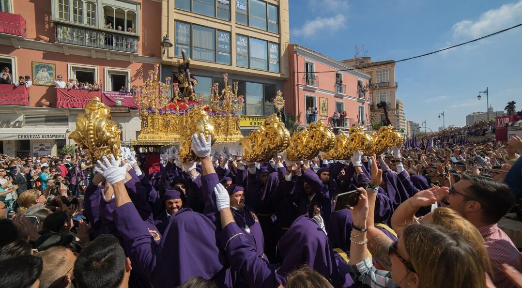 Hombres de trono llevando un trono en la Tribuna de los Pobres durante la Semana Santa de Málaga