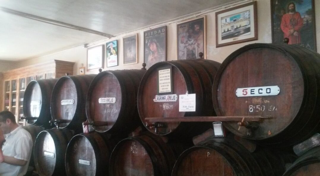 Toneles de vino dulce de Málaga etiquetados Seco y Pedro Ximénez en una bodega histórica del centro